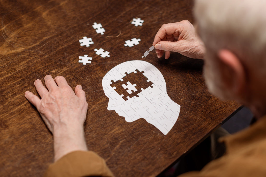Gehirn-Alterung stoppen - Senior spielt Puzzle in Gehirnform auf Holztisch